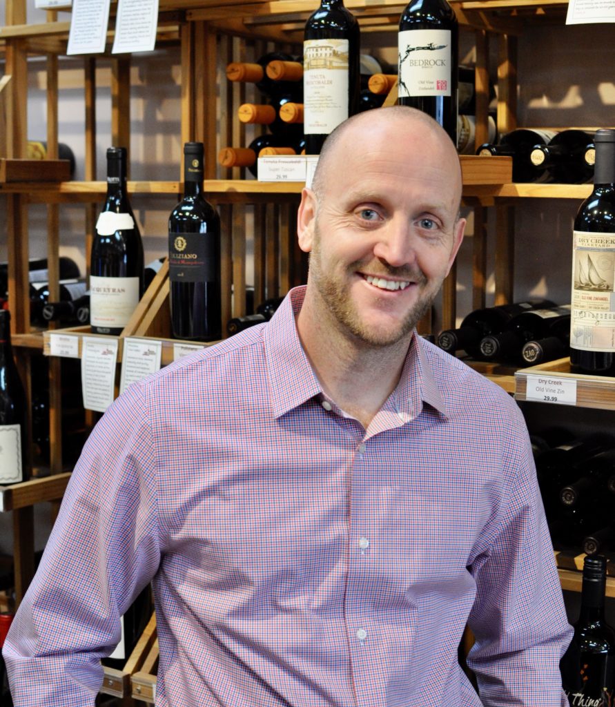 Picture of a man standing in front of wine bottles on a shelf